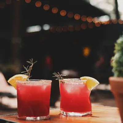 Två röda drinkar med apelsin på ett bord utomhus