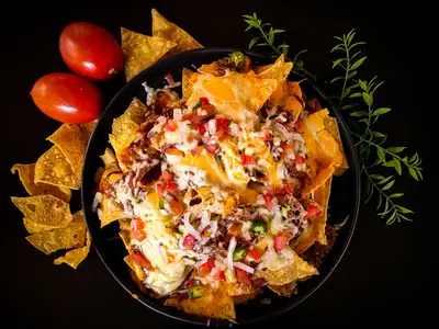 Ett stort fat nachos med ost, tomat och jalapeño