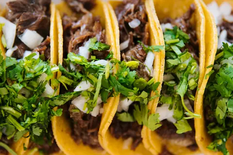 Rad av tacos med kött, lök och koriander