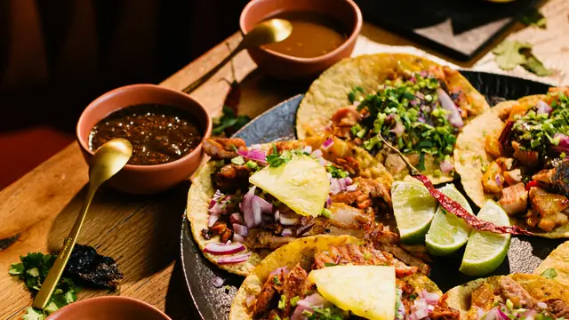 Ett bord med tacos, salsa och lime